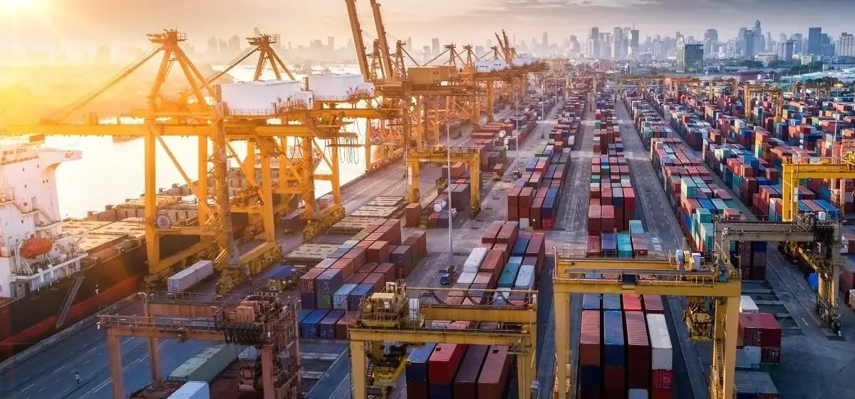 Container port at sunrise with a city skyline behind it